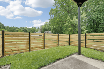 a wooden fence in a backyard with grass and trees at Rosen at North Hills, Raleigh, NC